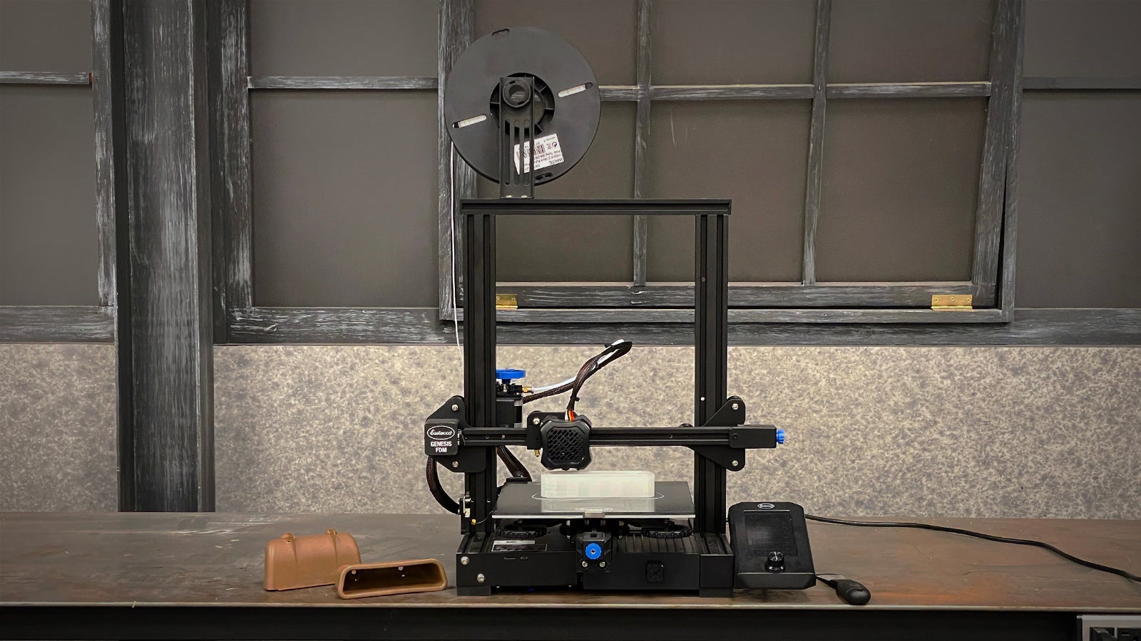 An Eastwood FDM 3D printer, next to the original part that it will soon replicate